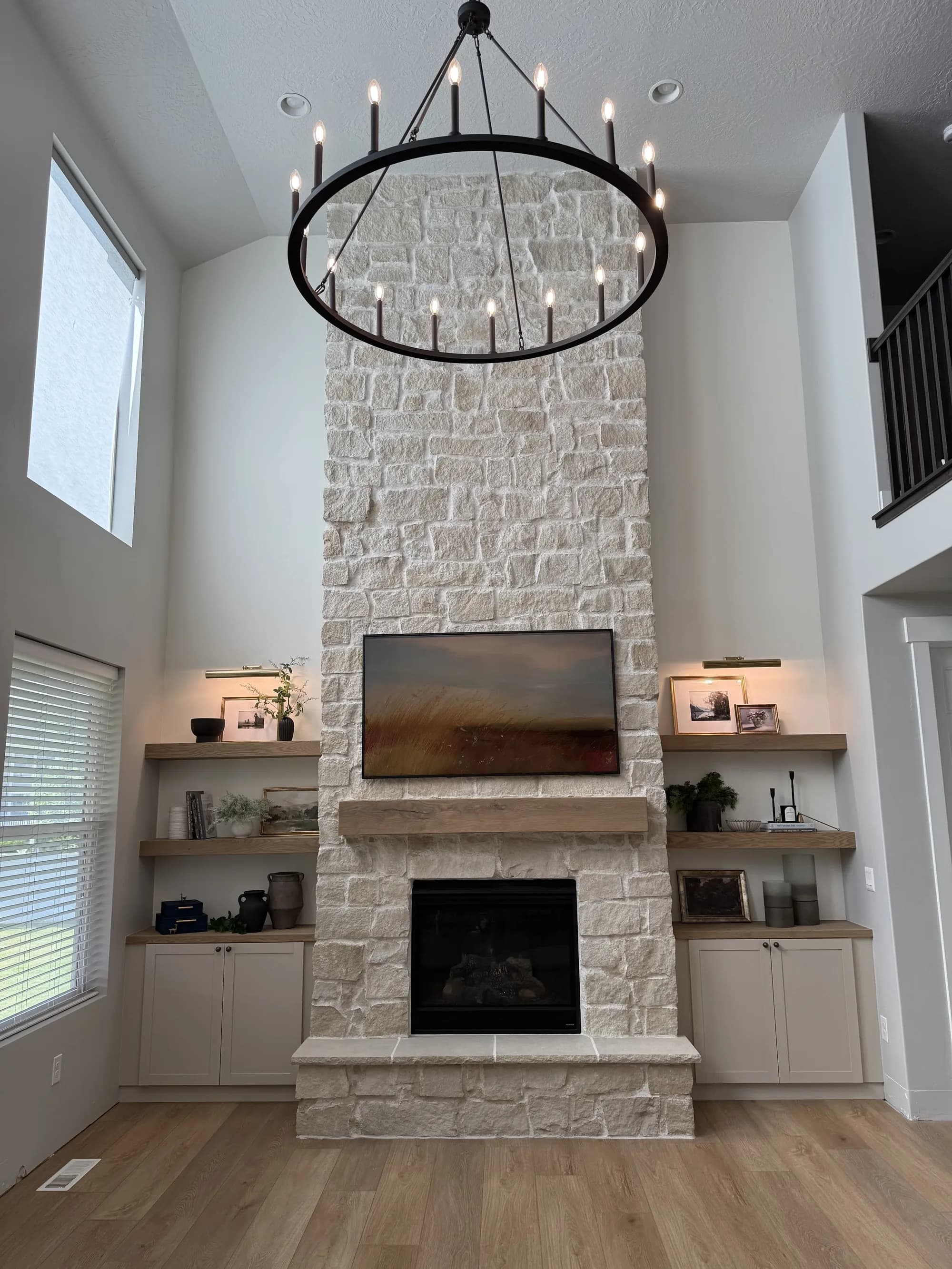 Stone fireplace with floating wood shelves and built-in cabinetry by BK Toolbox